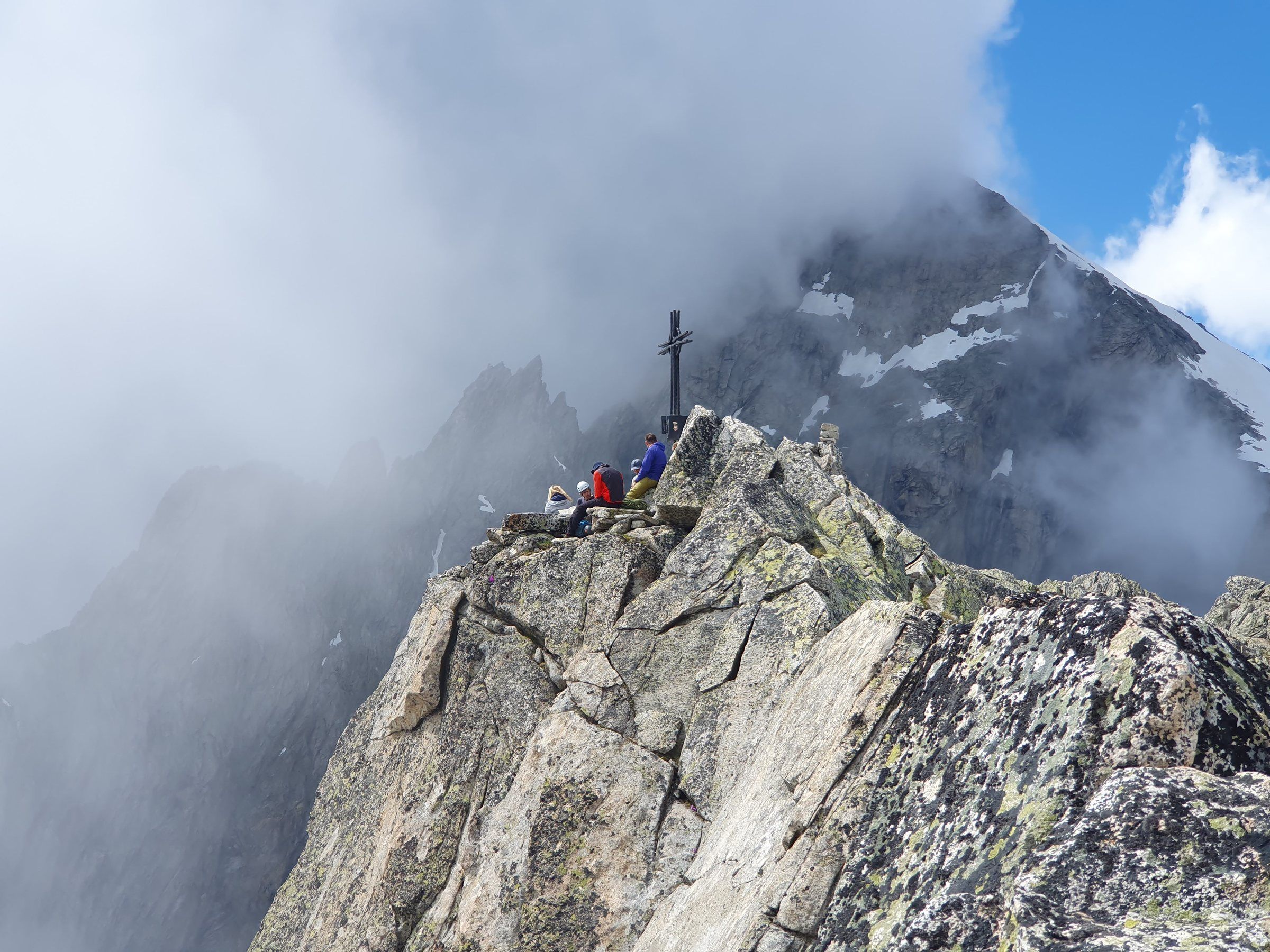 Gipfelkreuz auf einem Felsgrat im Nebel