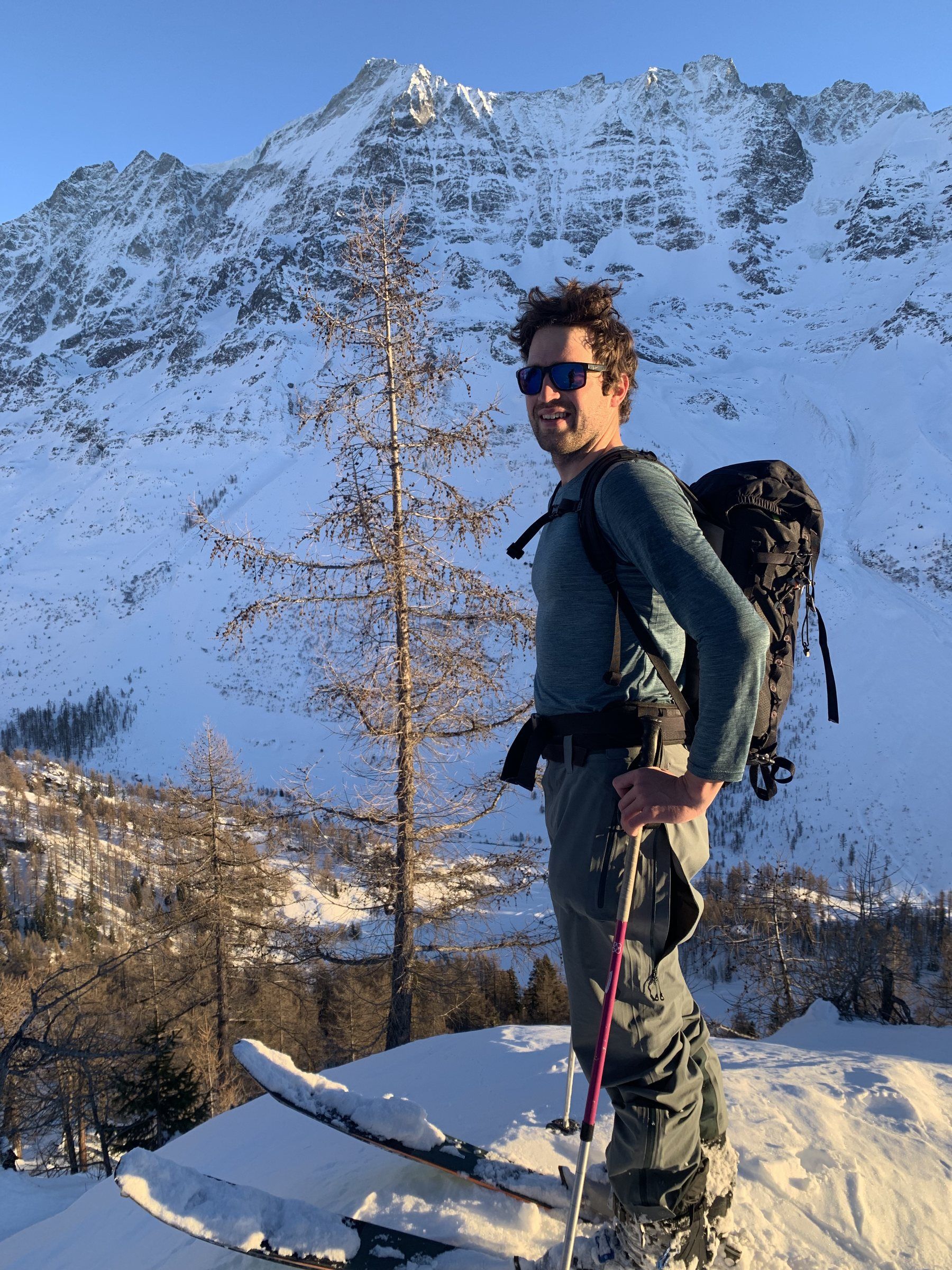 Manu mit Rucksack zwischen Lärchen im Winter