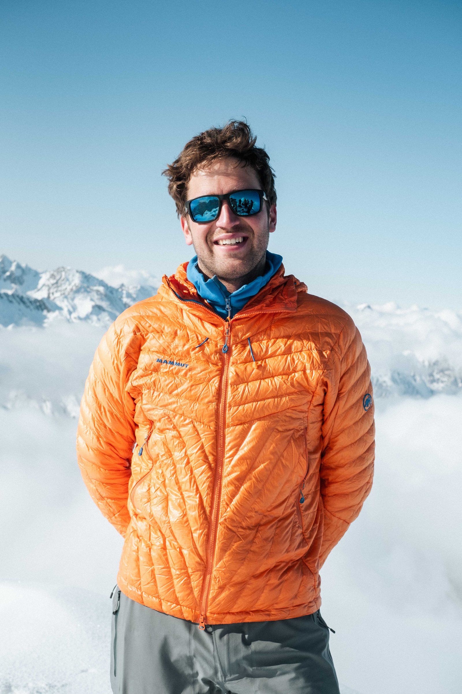 Manuel Stähelin in oranger Jacke vor einem Wolkenmeer