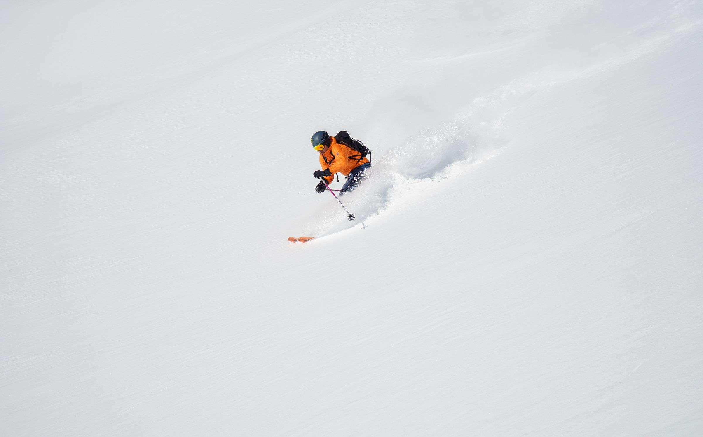 Skifahrer in orangem Anzug im Tiefschnee