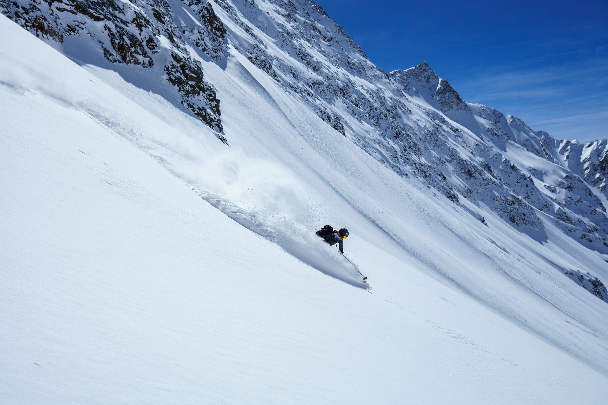 Skifahrer in einem Steilhang unter Felsen